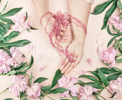 hands of a young girl with smooth skin and a bouquet of pink peo