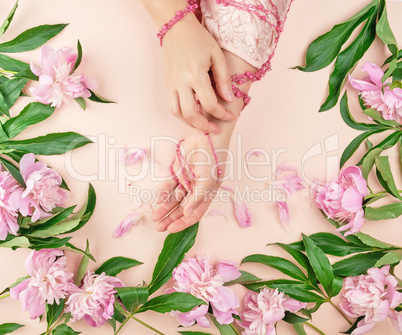 hands of a young girl with smooth skin and a bouquet of peonies