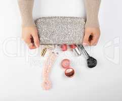 female hands and a silver cosmetic bag