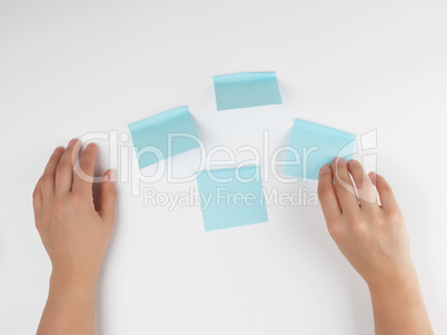 lot of blue stickers on a white background and two female hands