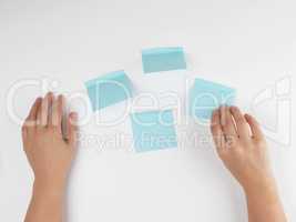 lot of blue stickers on a white background and two female hands