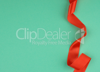 twisted red silk ribbon, green background, top view