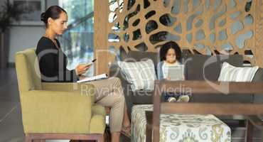 Mother and son using mobile phone and digital tablet in the lobby