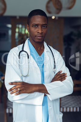 Male doctor standing with arms crossed in the lobby at hospital