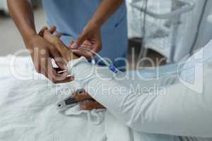 Female doctor attaching iv drip on female patient hand