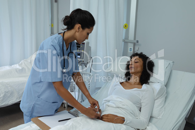 Female doctor attaching pulse oximetry on female patient hand in the ward