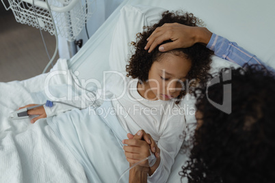 Mother holding hands of her son in the ward at hospital