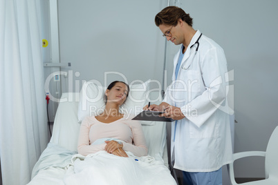 Male doctor interacting with female patient in the ward