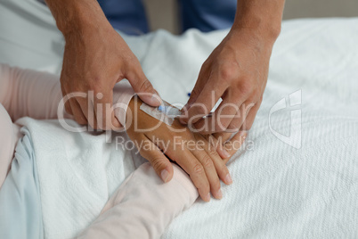 Doctor attaching iv drip on patient hand in the ward at hospital