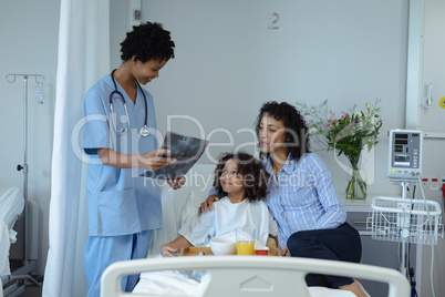 Female doctor discussing over x-ray report with mother and son in the ward