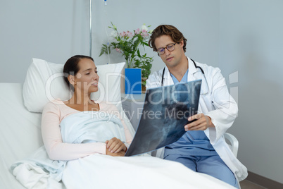 Male doctor interacting with female patient in the ward