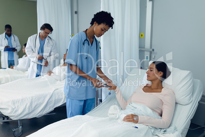 Female doctor attaching pulse oximetry on female patient hand in the ward