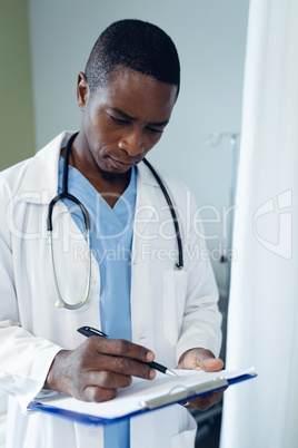 Male doctor checking medical report in the ward