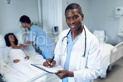 Male doctor writing on clipboard in the ward at hospital