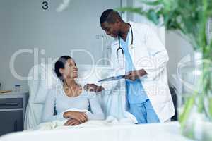 Male doctor interacting with female patient in the ward