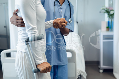 Female doctor helping female patient to walk in the ward at hospital