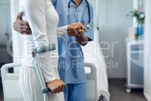Female doctor helping female patient to walk in the ward at hospital