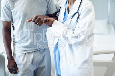 Female doctor helping male patient to walk in the ward at hospital