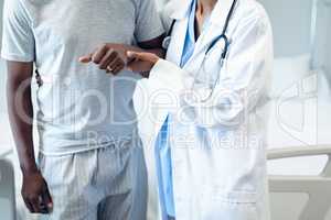 Female doctor helping male patient to walk in the ward at hospital