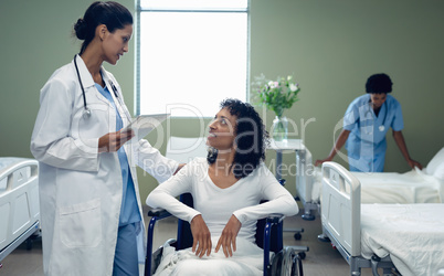 Female doctor interacting with disabled female patient in the ward