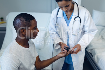 Female doctor taking patients blood sample with lancet pen in the ward