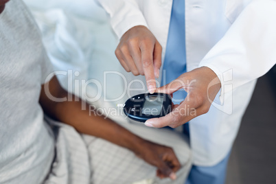 Female doctor taking patients blood sample with lancet pen in the ward