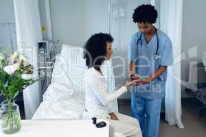 Female doctor taking patients blood sample with lancet pen in the ward