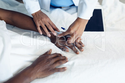 Female doctor attaching iv drip on male patient hand in the ward