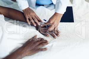 Female doctor attaching iv drip on male patient hand in the ward