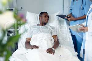 Female doctors interacting with male patient in the ward