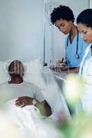 Female doctors checking male patient in the ward