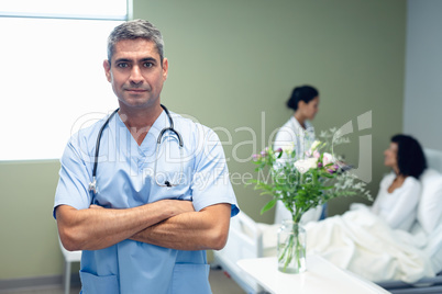 Male doctor standing with arms crossed in the ward at hospital