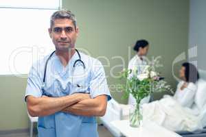 Male doctor standing with arms crossed in the ward at hospital