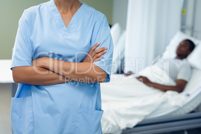 Female doctor standing with arms crossed in the ward at hospital