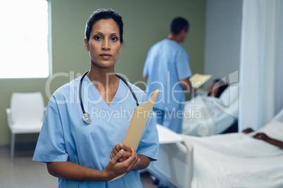 Female doctor standing with file in the ward at hospital