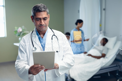 Male doctor using digital tablet in the ward at hospital