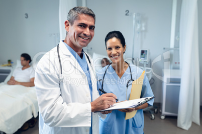 Male doctor writing on clipboard in the ward at hospital