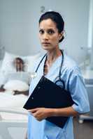 Female doctor standing with clipboard in the ward at hospital
