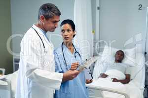 Male and female doctors discussing over digital tablet in the ward