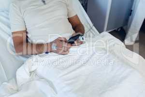 Male patient using mobile phone in the ward at hospital