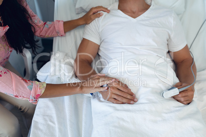 Woman consoling male patient in the ward at hospital