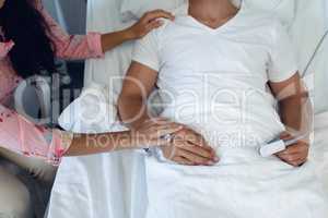 Woman consoling male patient in the ward at hospital