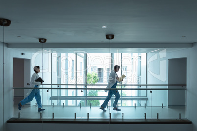 Female and male doctors running in the corridor at hospital