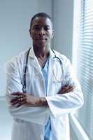 Male doctor standing with arms crossed in hospital