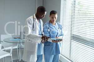 Male and female doctors looking at file in the hospital