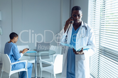 Male doctor talking on mobile phone in hospital Male doctor talking on mobile phone in hospital