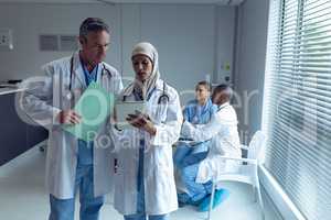 Male and female doctors discussing over digital tablet in hospital