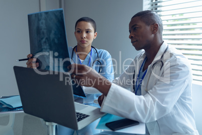 Male and female doctors looking at x-ray report in hospital
