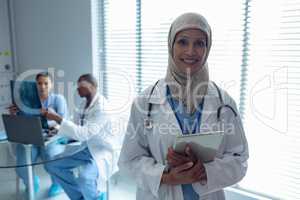Female doctor in hijab standing with digital tablet in hospital