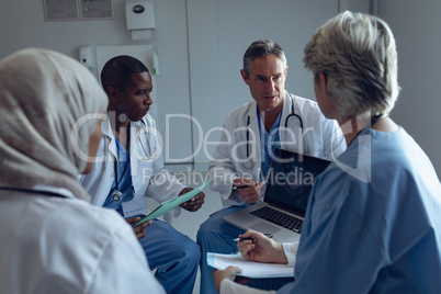 Medical team discussing over laptop in hospital